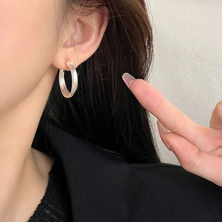 Silberne Creolen-Ohrringe an Ohr, eleganter Schmuck, modisches Accessoire für Damen.