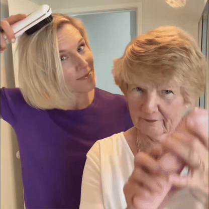 Kvinna i lila tröja borstar sitt blonda hår med en vit värmeborste medan en äldre kvinna med kort hår står framför. 9