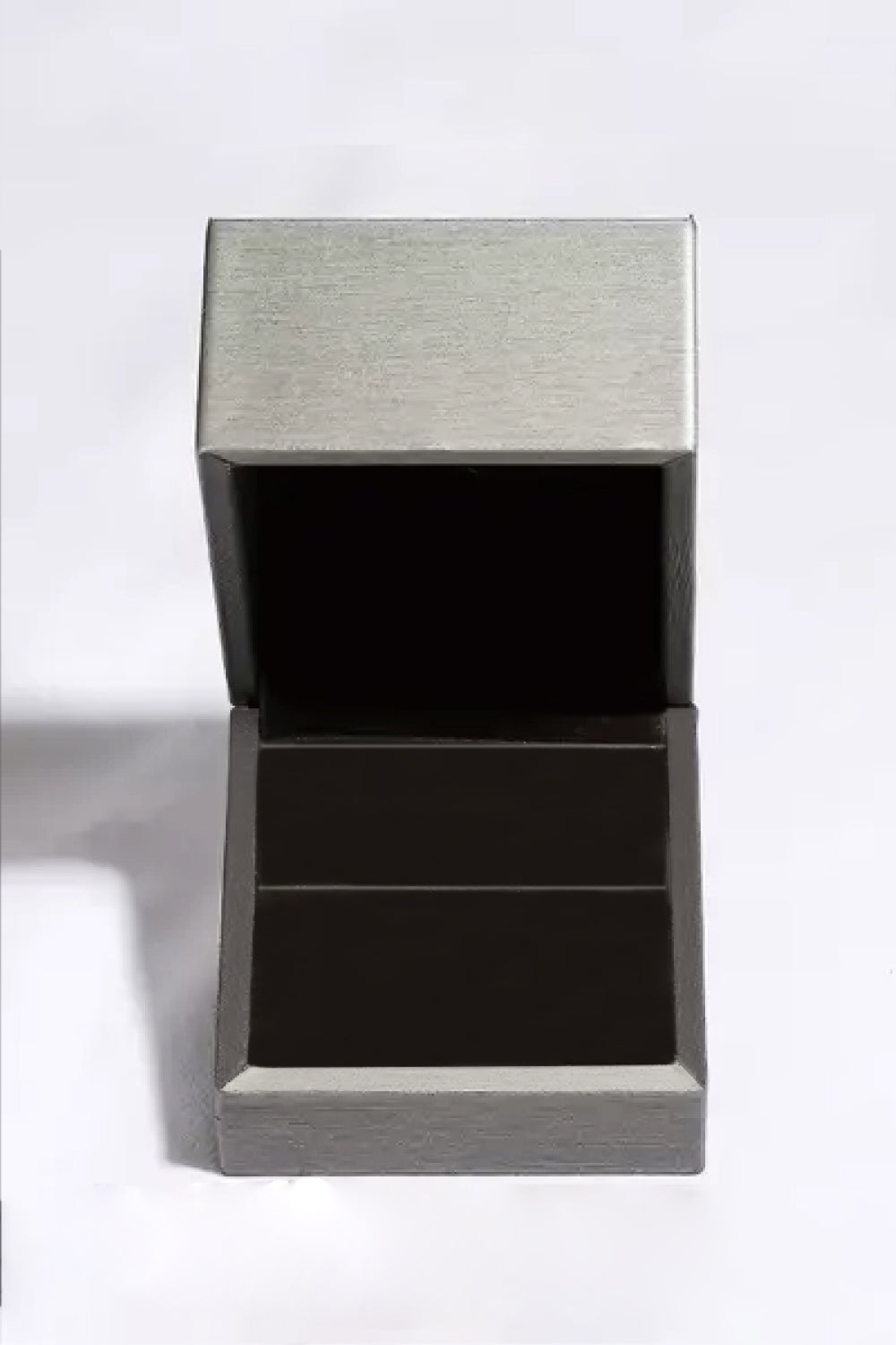 Leere silberne Schmuckschatulle, quadratisch, offen, aus Metall, auf weißem Hintergrund.