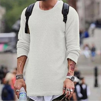 Mann in weißem Strickpullover mit Rucksack, urbaner Hintergrund, modischer Freizeitlook.