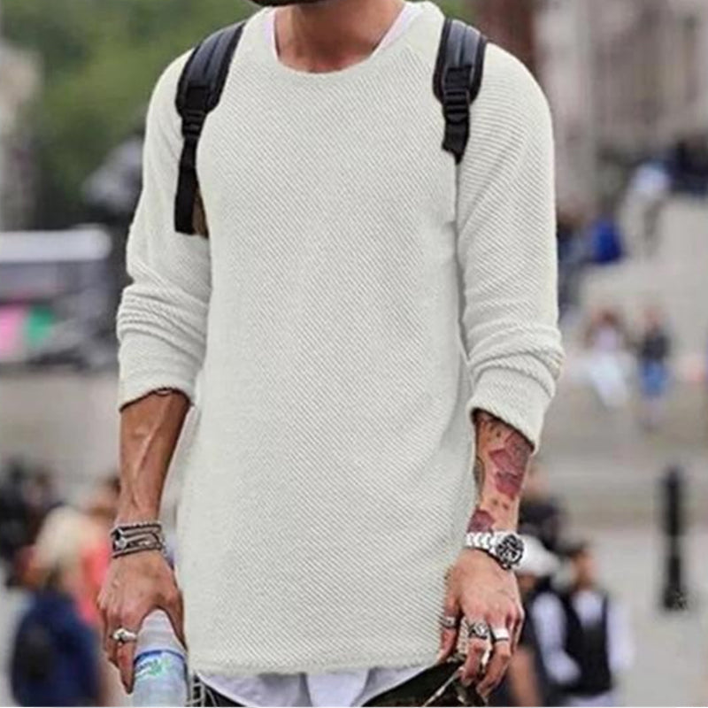 Mann in weißem Strickpullover mit Rucksack, urbaner Hintergrund, modischer Streetwear-Look.