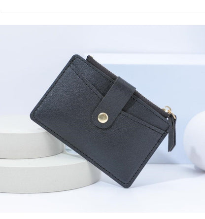 Schwarzes Leder-Kartenetui mit Druckknopf, minimalistisches Design, stilvoll und praktisch.