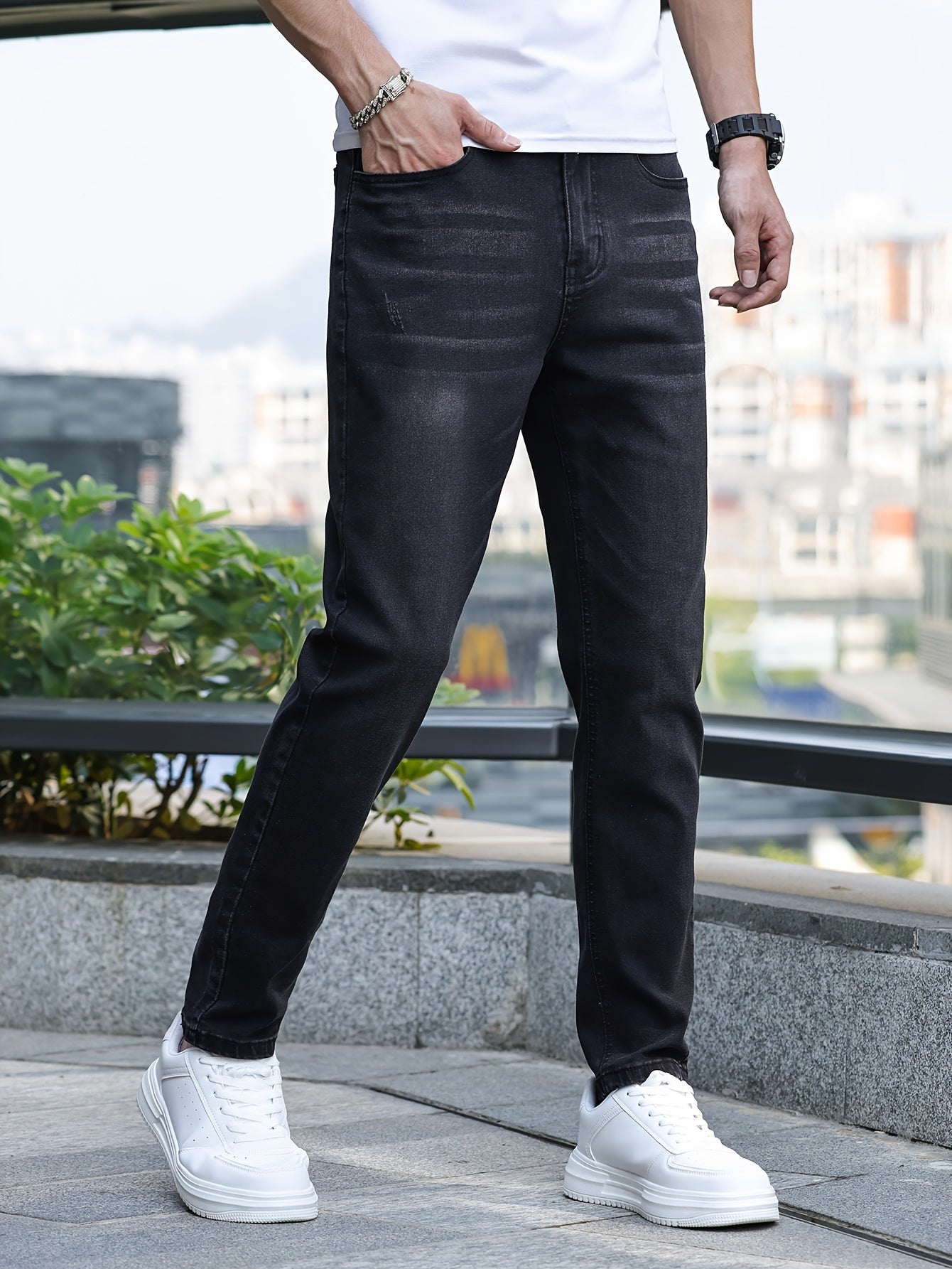 Mann in schwarzer Jeans und weißen Sneakers, urbaner Hintergrund, lässige Mode.