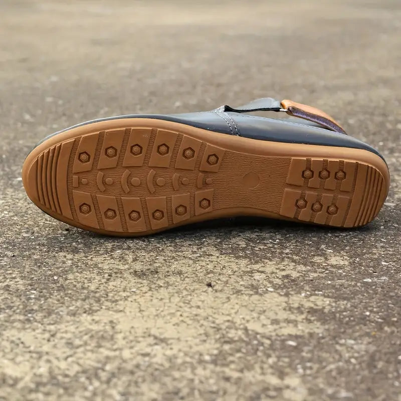 Schwarze Lederschuhe mit rutschfester Gummisohle auf Betonboden.