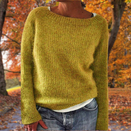 Senapsgul stickad tröja med rund hals och långa ärmar, bärd av en modell över vitt linne och jeans i en höstskog. 1