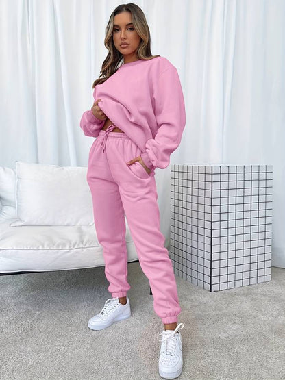 Frau in rosa Jogginganzug, weiße Sneaker, modernes Wohnzimmer, gemütliche Mode, Freizeitkleidung.