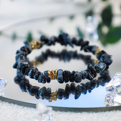 Schwarzes Edelsteinarmband mit goldenen Akzenten auf Spiegel, Schmuck, elegant, modisch.