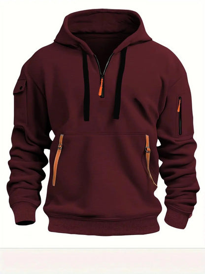 Vinröd hoodie sedd framifrån med halv dragkedja, svarta dragsnören, orange detaljer på fickornas dragkedjor och ärmfickor på båda armarna. 5