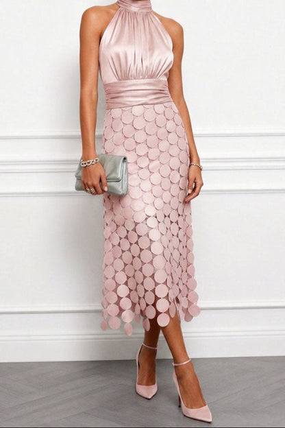 Modell i dammrosa midiklänning med skimrande satinliv och cirkelapplikationer på kjolen, med grå clutch och rosa klackskor. 3