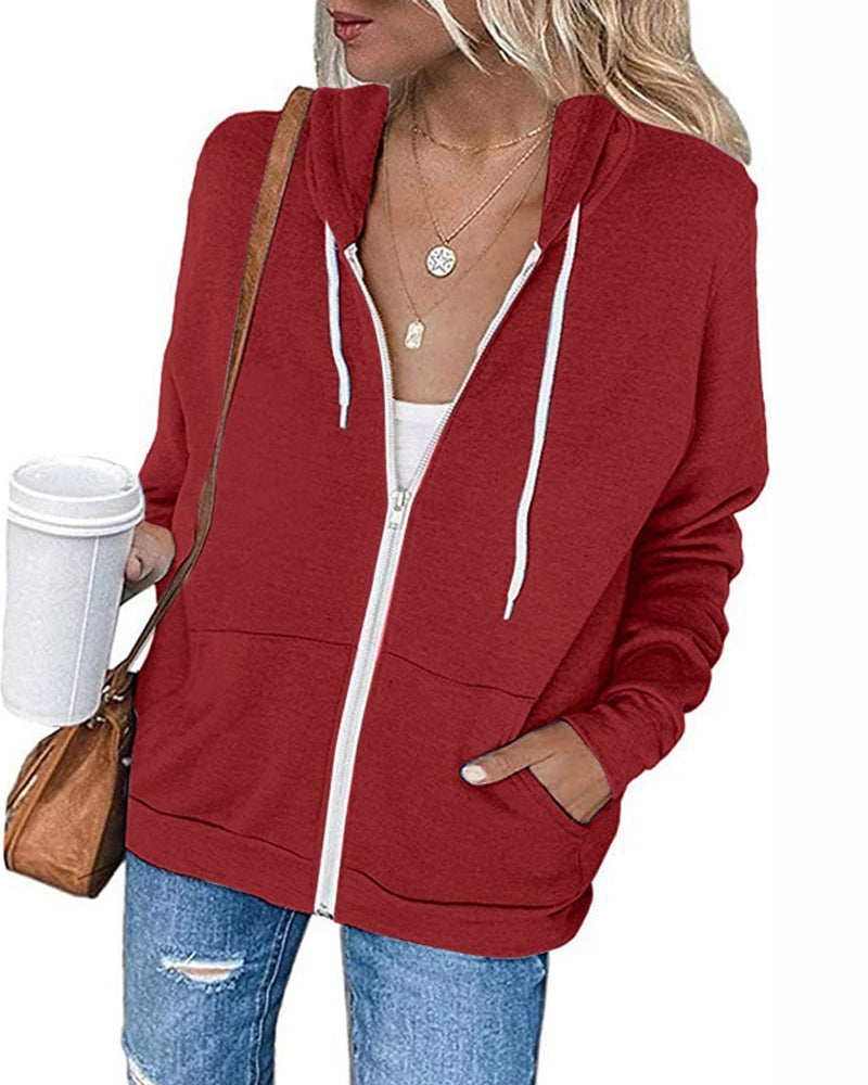 Frau in rotem Kapuzenpullover mit Reißverschluss, Kaffeebecher, Jeans, braune Tasche.