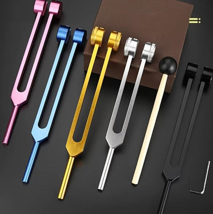 Bunte Stimmgabeln aus Metall, Set mit fünf Farben, auf schwarzem Hintergrund.