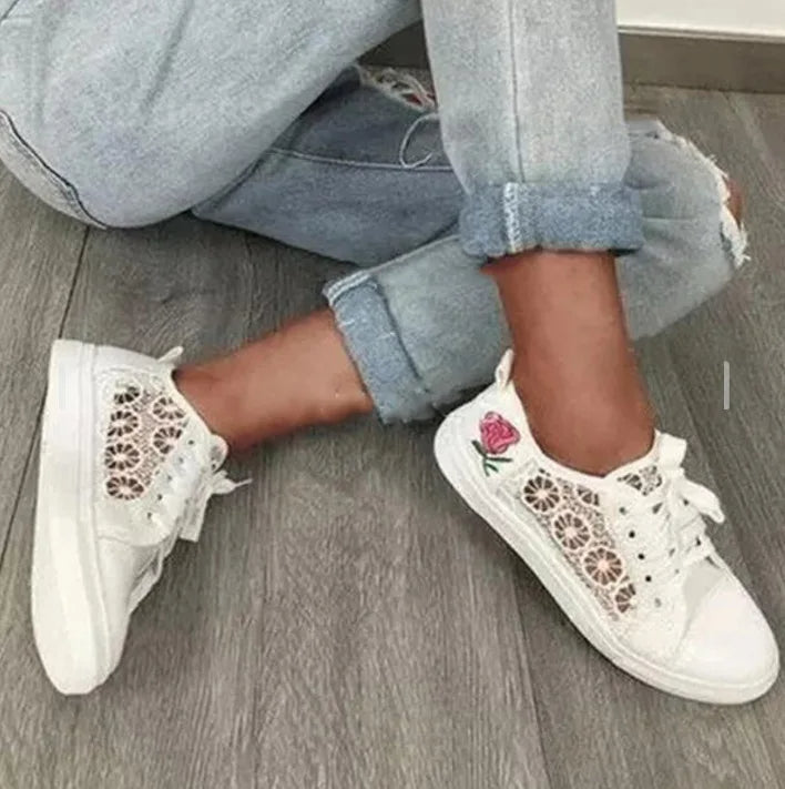 Weiße Damen-Sneaker mit Spitze und Rosenstickerei, lässig, modisch, auf Holzboden.