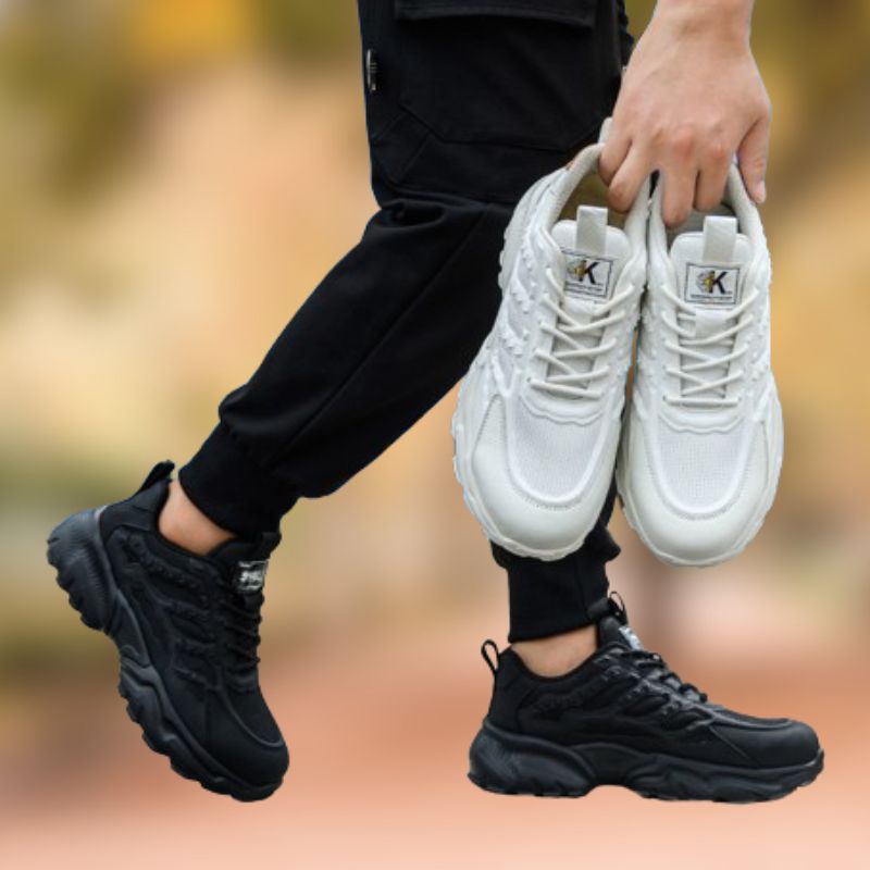 Person hält weiße und trägt schwarze Sneaker, sportlich, modern, bequem, Unisex-Schuhe.