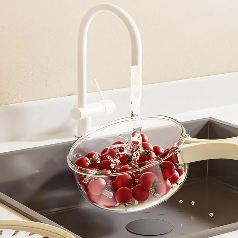 Durchsichtiger Kunststoffsieb mit roten Kirschtomaten unter Wasserhahn in moderner Küche.