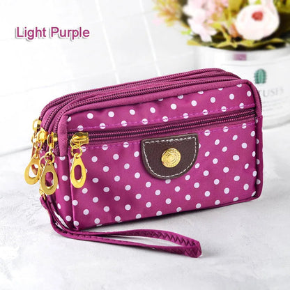 Lila gepunktete Damenhandtasche mit Reißverschluss, modisch, kompakt, aus Stoff.
