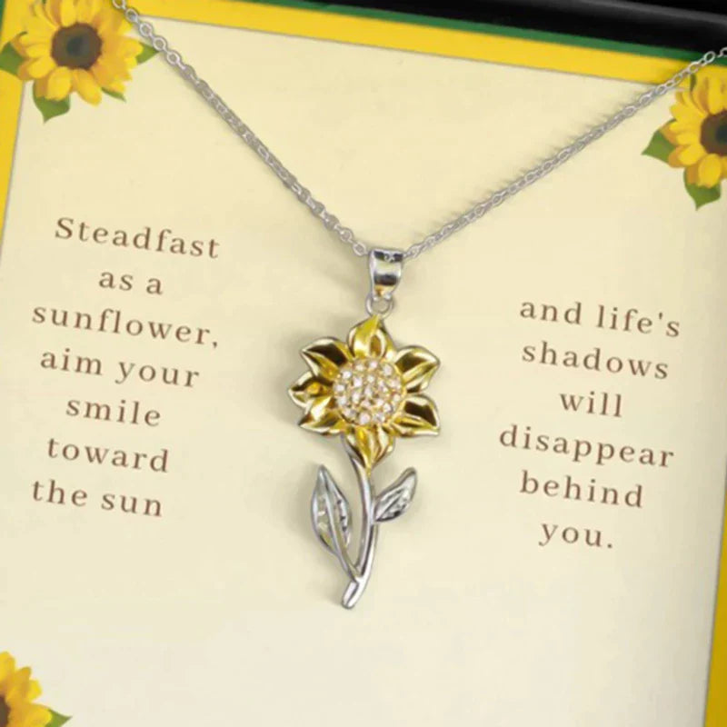 Silberne Sonnenblumen-Halskette mit gelbem Blütenanhänger auf Geschenkbox mit Zitat.