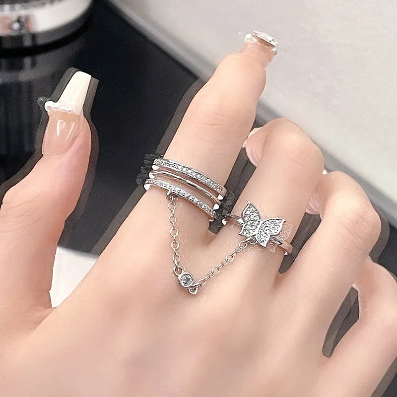 Damenhand mit silbernen Ringen, Schmetterlingsdesign, Kettendetail, eleganter Schmuck.