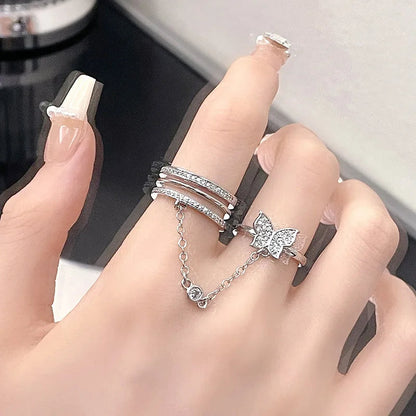 Damenhand mit silbernen Ringen, Schmetterlingsdesign, Kettendetail, eleganter Schmuck.