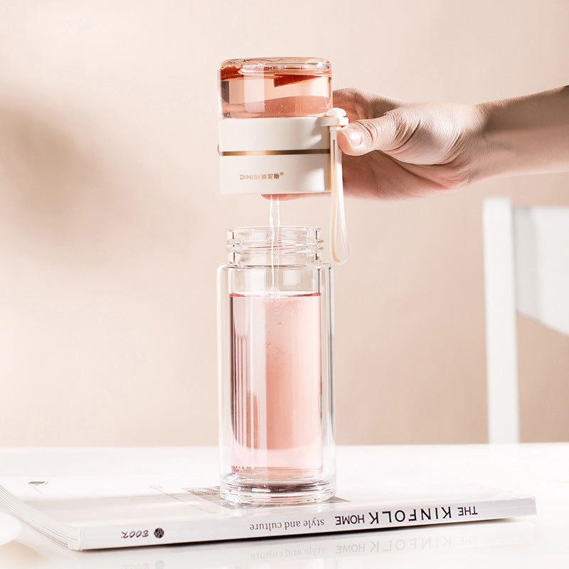 Hand gießt Wasser in transparenten Wasserfilterflasche, modernes Design, auf Tisch.