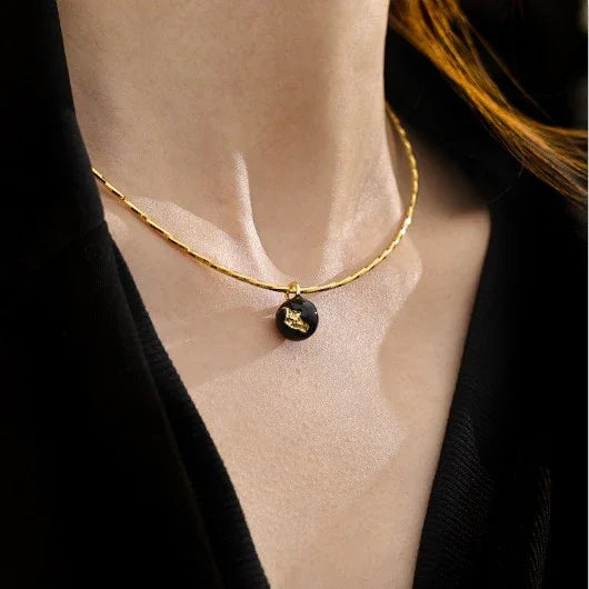 Goldene Halskette mit schwarzem Anhänger, eleganter Schmuck für Damen, modisches Accessoire.