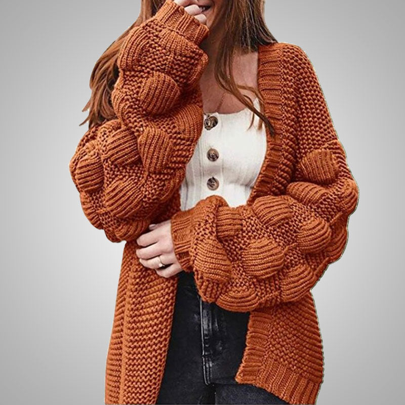 Frau in orange Strickjacke mit Puffärmeln, weißem Oberteil, schwarze Jeans, Herbstmode.