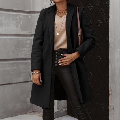 Frau in schwarzem Wollmantel, Lederhose, beige Pullover, Goldschmuck, modisch, elegant.