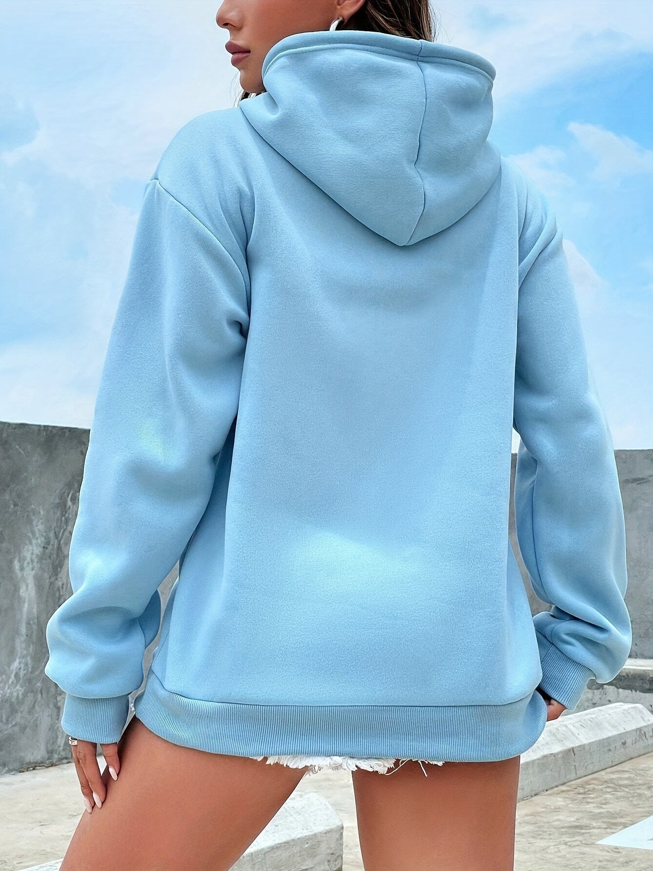 Frau in hellblauem Kapuzenpullover, lässig, modisch, urbaner Stil, Outdoor-Hintergrund.