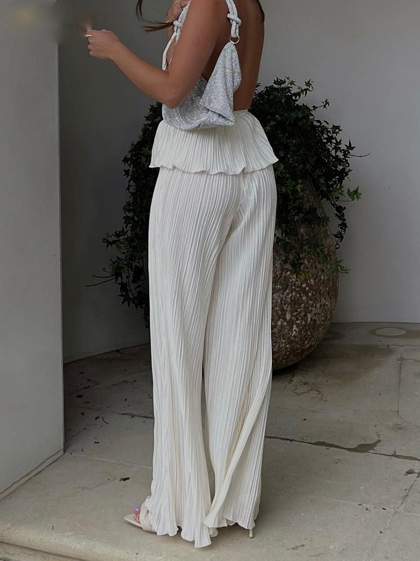 Frau in weißer, plissierter Hose und silbernem Top, modisch, elegant, Sommeroutfit.