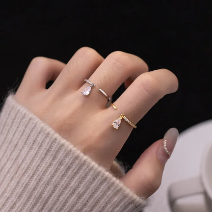 Hand mit drei eleganten Ringen, Tropfenform, Silber und Gold, Damenmode, Schmucktrends.