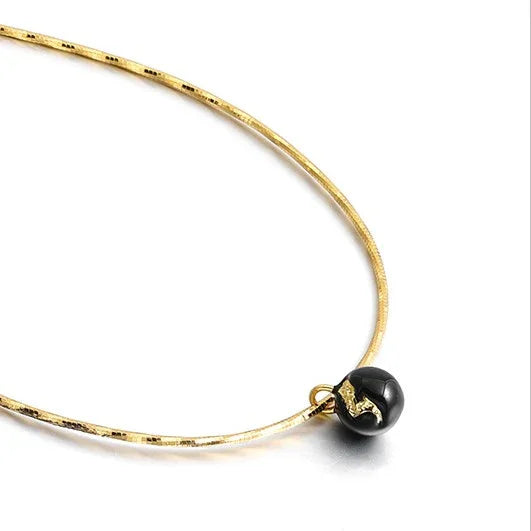 Goldene Halskette mit schwarzem Anhänger, elegantes Schmuckdesign, Damenaccessoire.