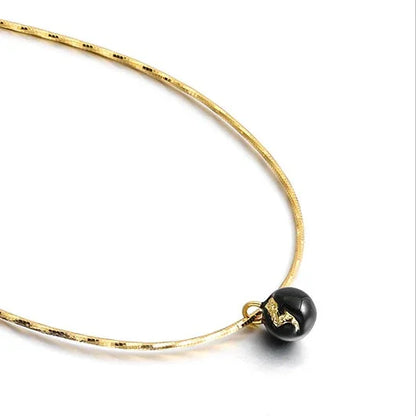 Goldene Halskette mit schwarzem Anhänger, elegantes Schmuckdesign, Damenaccessoire.