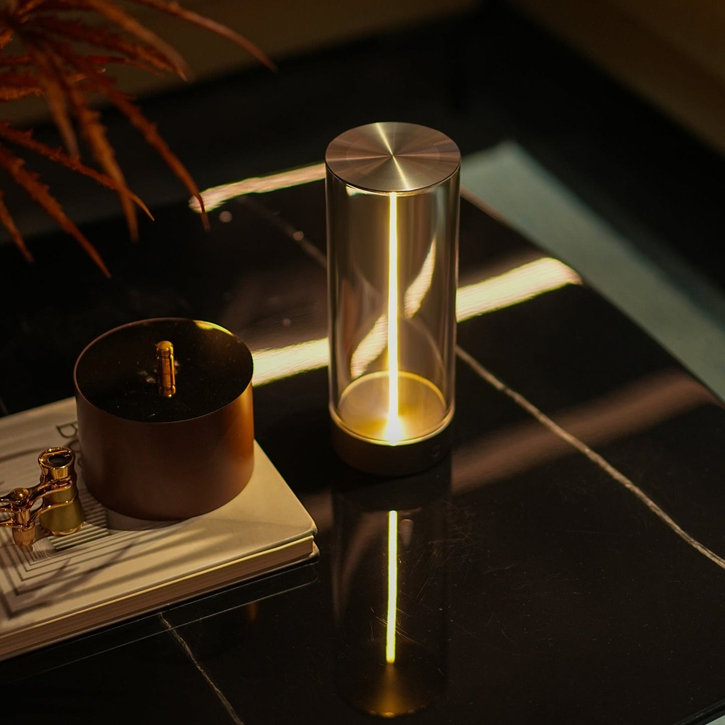 Moderne LED-Tischlampe aus Glas und Metall auf schwarzem Marmortisch, stilvolle Beleuchtung.