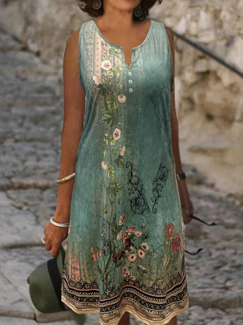 Frau in ärmellosem, geblümtem Sommerkleid, grün, auf Kopfsteinpflasterweg.