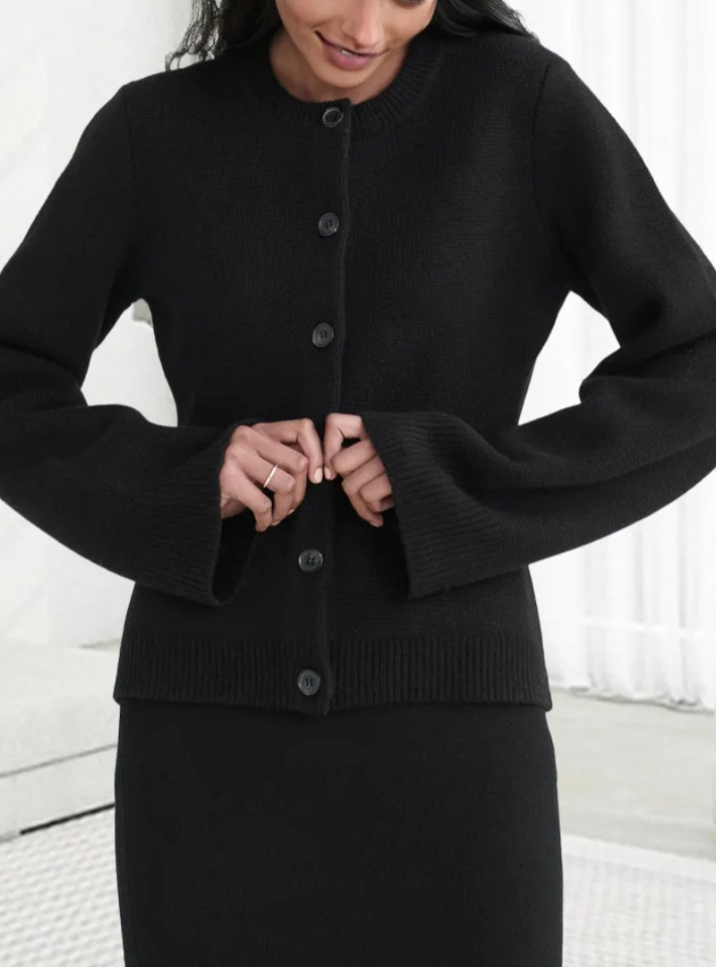 Frau trägt schwarze Strickjacke mit Knöpfen, elegantes Design, Damenmode, Herbstbekleidung.