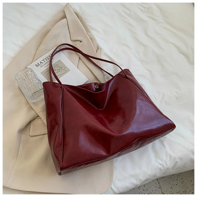 Dunkelrote Ledertasche auf beigem Mantel, elegantes Design, Damenmode Accessoire.