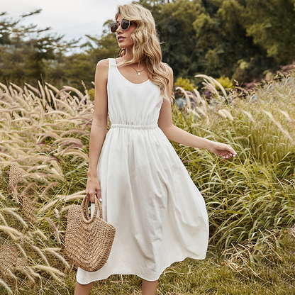Frau im weißen Sommerkleid mit Strohtasche in einem Feld, Sonnenbrille, blonde Haare.