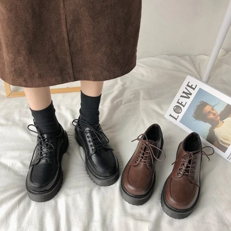 Schwarze und braune Schnürschuhe aus Leder auf Teppich neben Zeitschrift.