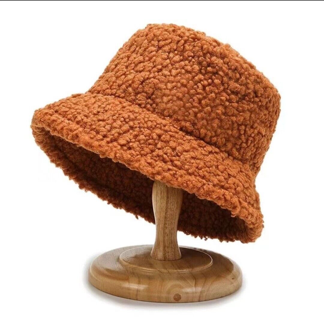 Brauner Teddyfleece-Bucket-Hut auf Holzständer, modisch, warm, Winteraccessoire.