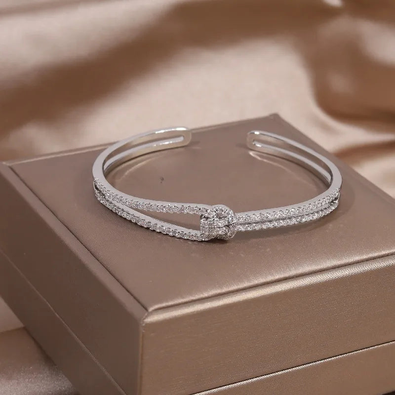 Silbernes Armreif mit Strasssteinen auf beigem Hintergrund, eleganter Schmuck, Damenaccessoire.