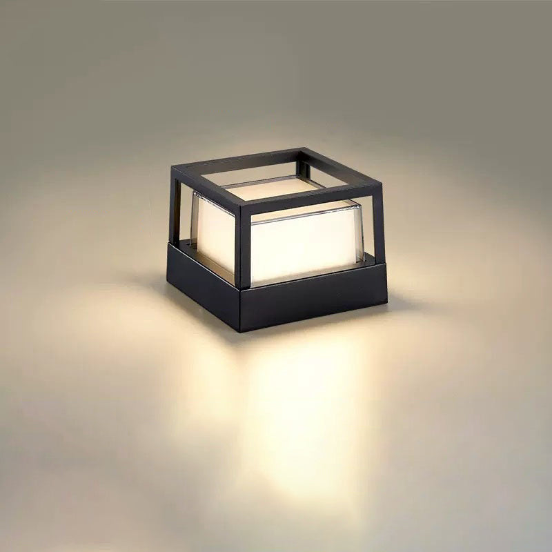 Fyrkantig svart lampa med öppen kubformad ram upptill och lysande vit skärm på neutral bakgrund. 11
