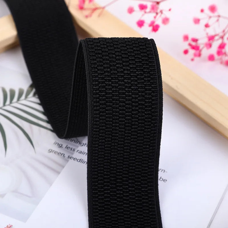 Schwarzes elastisches Band, gewebt, für Nähprojekte, 3 cm breit, auf floralem Hintergrund.