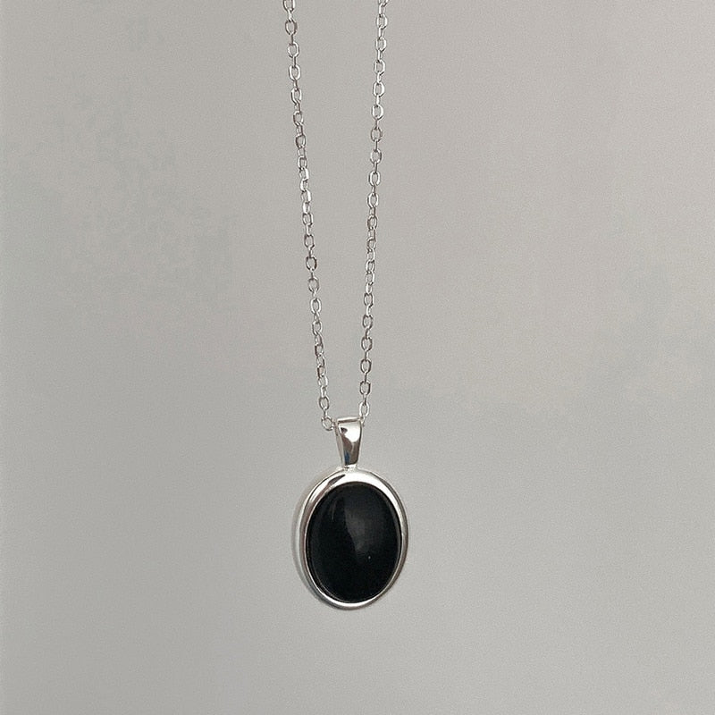 Silberkette mit schwarzem ovalem Anhänger, eleganter Schmuck, minimalistisches Design.