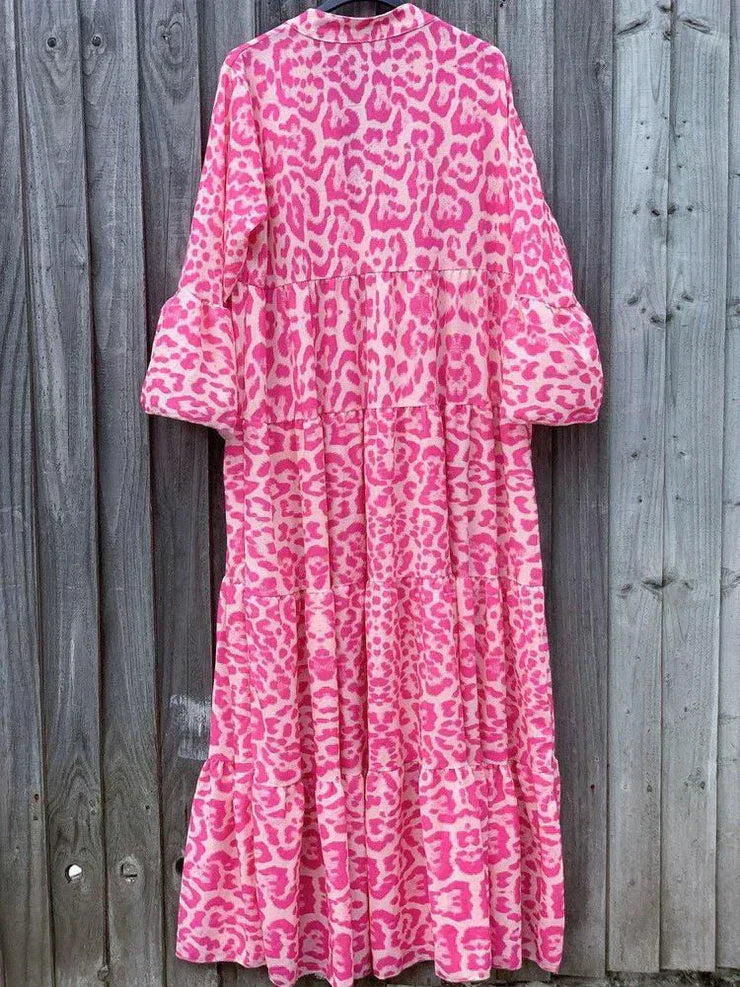 Rosa Maxikleid mit Leopardenmuster, langärmelig, aus Baumwolle, vor Holzwand.