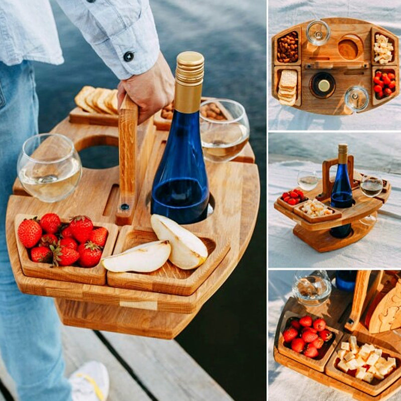 Holz-Picknicktisch mit Weinflasche, Gläsern, Obst und Käse, ideal für Outdoor-Aktivitäten.