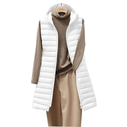 Weiße Damen-Steppweste mit Kapuze, über braunem Pullover und beigen Hosen, modisch, elegant.