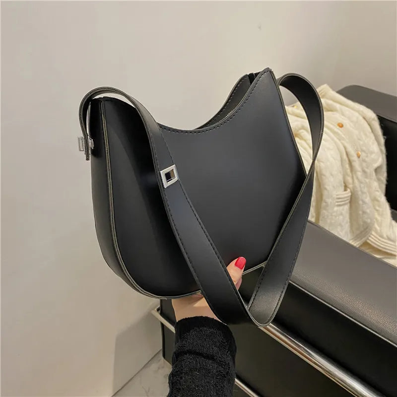 Schwarze Lederhandtasche mit breitem Schulterriemen, modisches Accessoire für Damen.