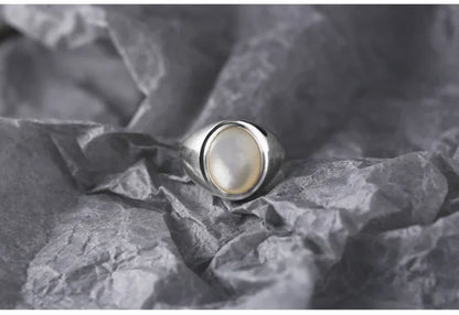 Silberring mit Perlmuttstein auf grauem Hintergrund, eleganter Schmuck für Damen.