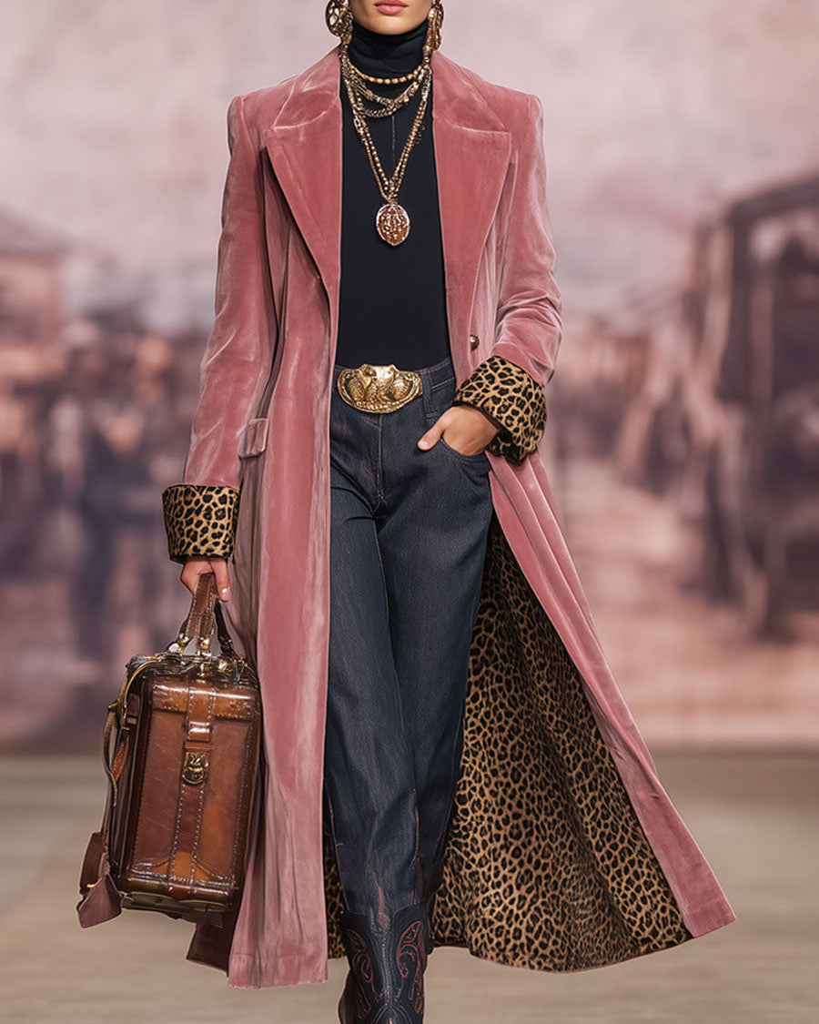 Modell på catwalk i rosa sammetskappa med leopardfoder, guldsmycken, brun lädervæska och handen i fickan framifrån. 3