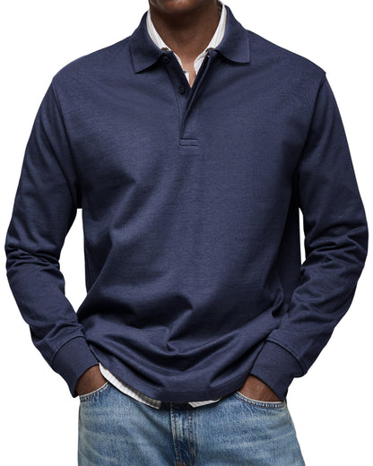 Marinblå långärmad pikétröja sedd framifrån på en modell med händerna i fickorna, över randig skjorta och jeans. 3
