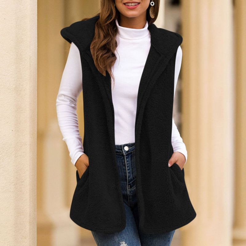 Frau trägt schwarze ärmellose Weste, weiße Bluse, blaue Jeans, modisch, elegant, Herbstmode.